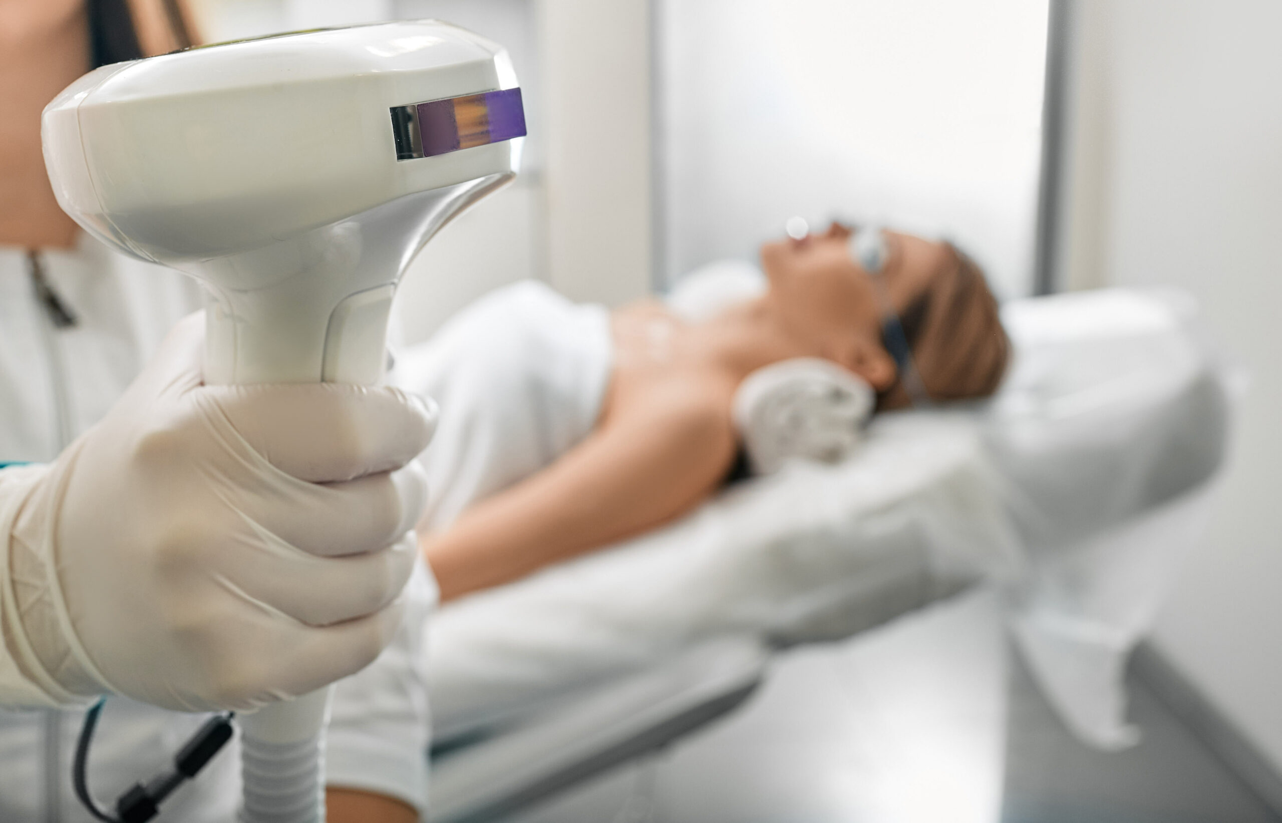 Beautician holding Lumecca device with intense pulsed light IPL technology for photorejuvenation of a woman's body and removal of brown spots and freckles, close-up | RefineKC Aesthetics in Kansas City, MO