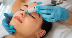 Woman receiving HydraFacial treatment on nose by a professional wearing blue gloves in Kansas City, MO